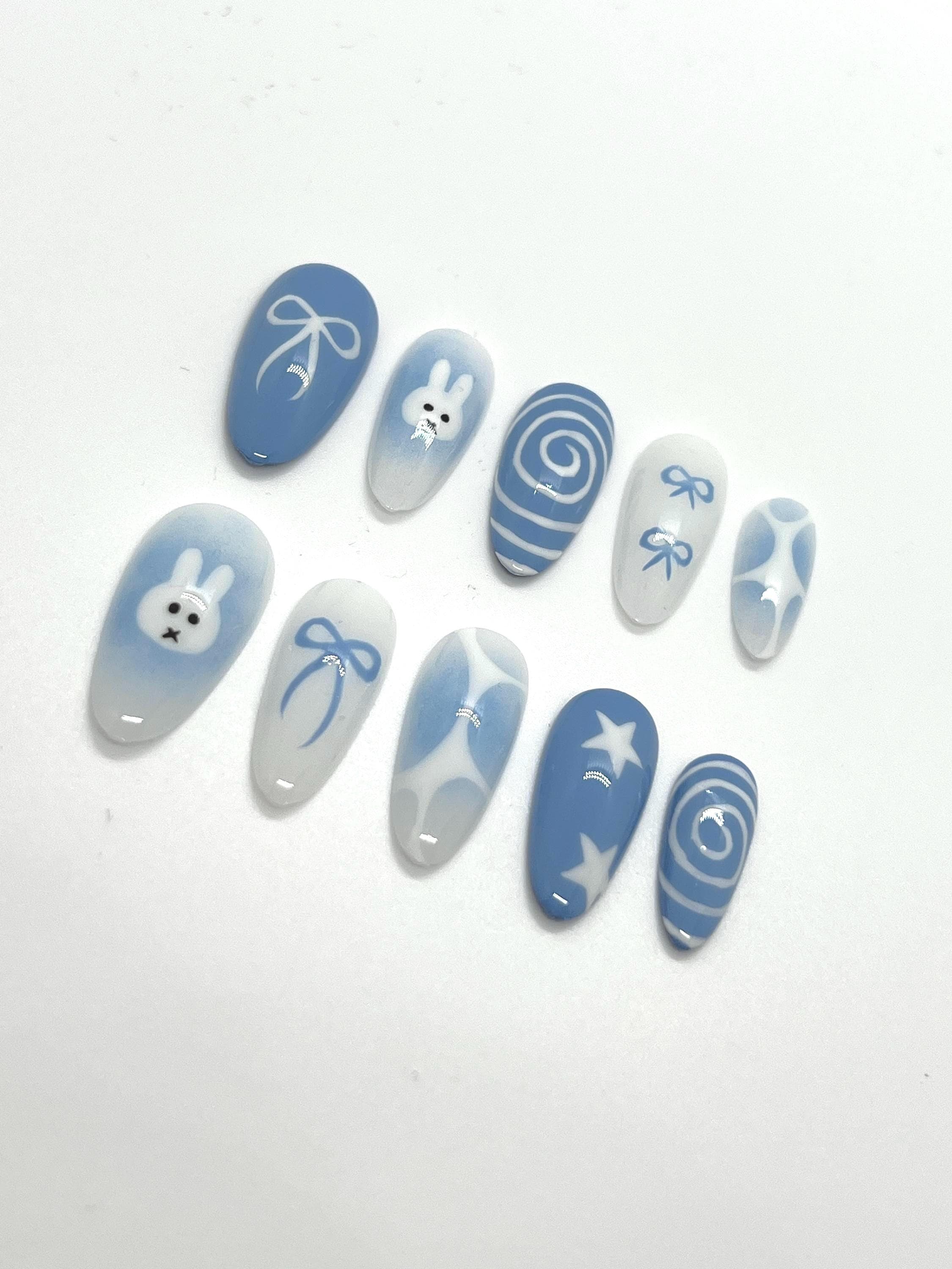 Handmade blue press-on nails with Miffy-inspired design on a white background