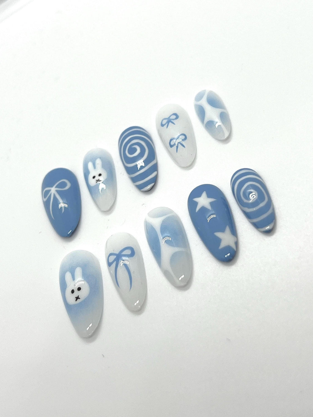 Handmade blue press-on nails with Miffy-inspired design on a white background