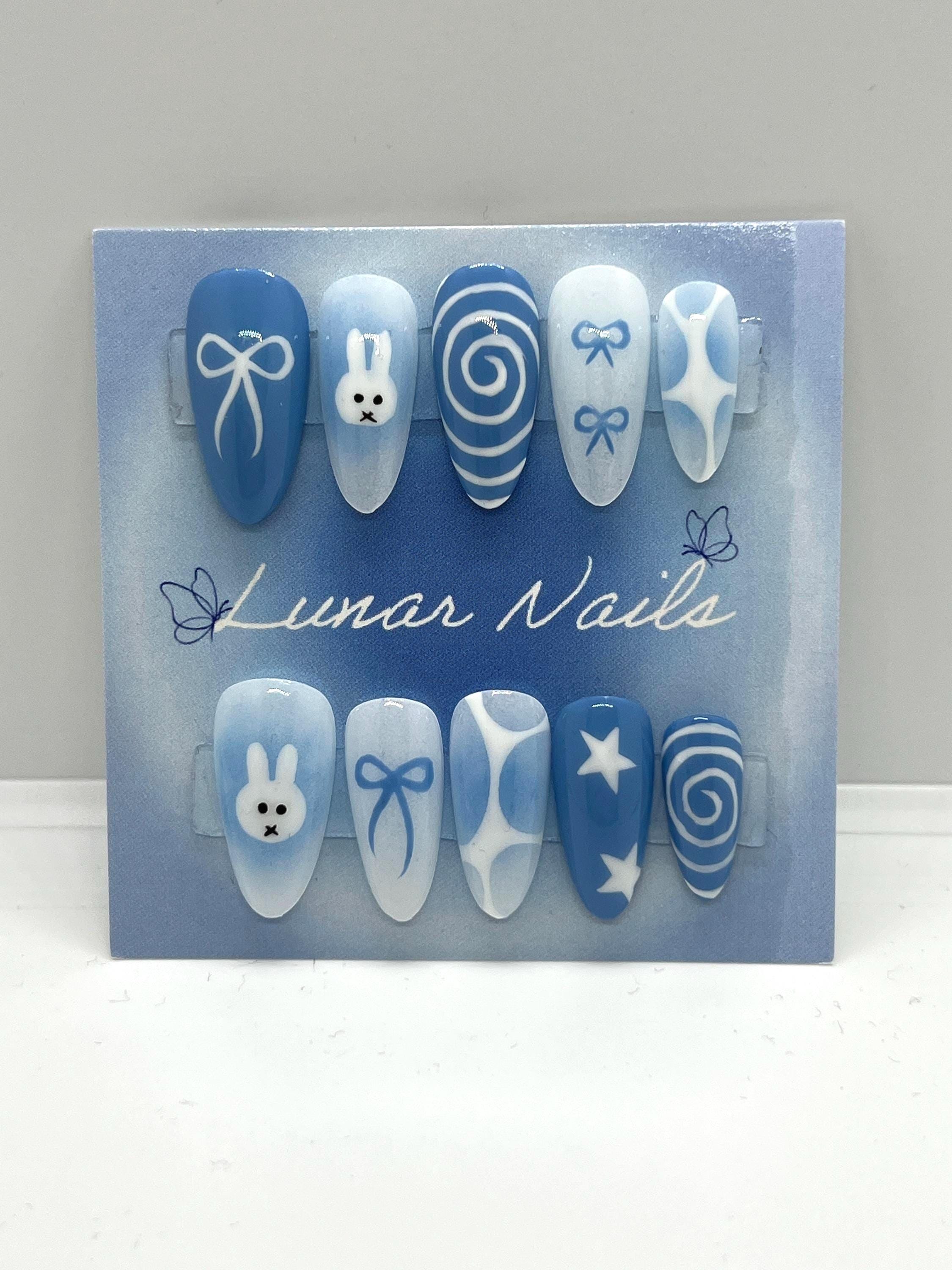 Set of blue and white nail art designs on a display card with 'Lunar Nails' branding.